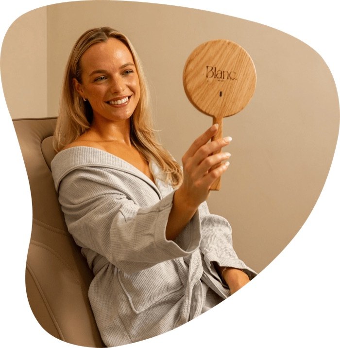 Guest at Blanc Health holding the studio's signature hand mirror